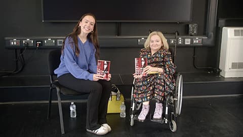 Penny at Loughborough Literary Festival 2025 holding her fourth book The Woman Next Door and she is smiling.